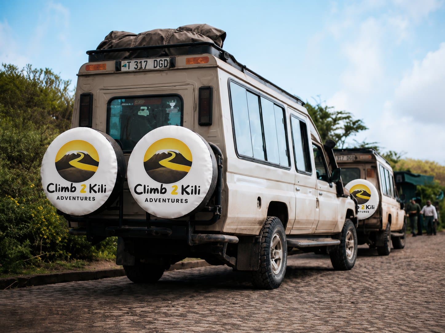 Fondateur debout avec des guides Kilimandjaro, des porteurs, des chefs, des chauffeurs et des membres de la communauté locale sous le mont Kilimandjaro